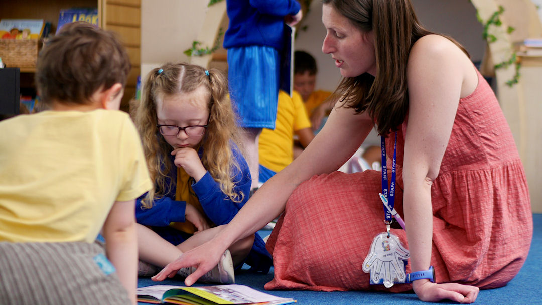 A teacher reading a book with two children